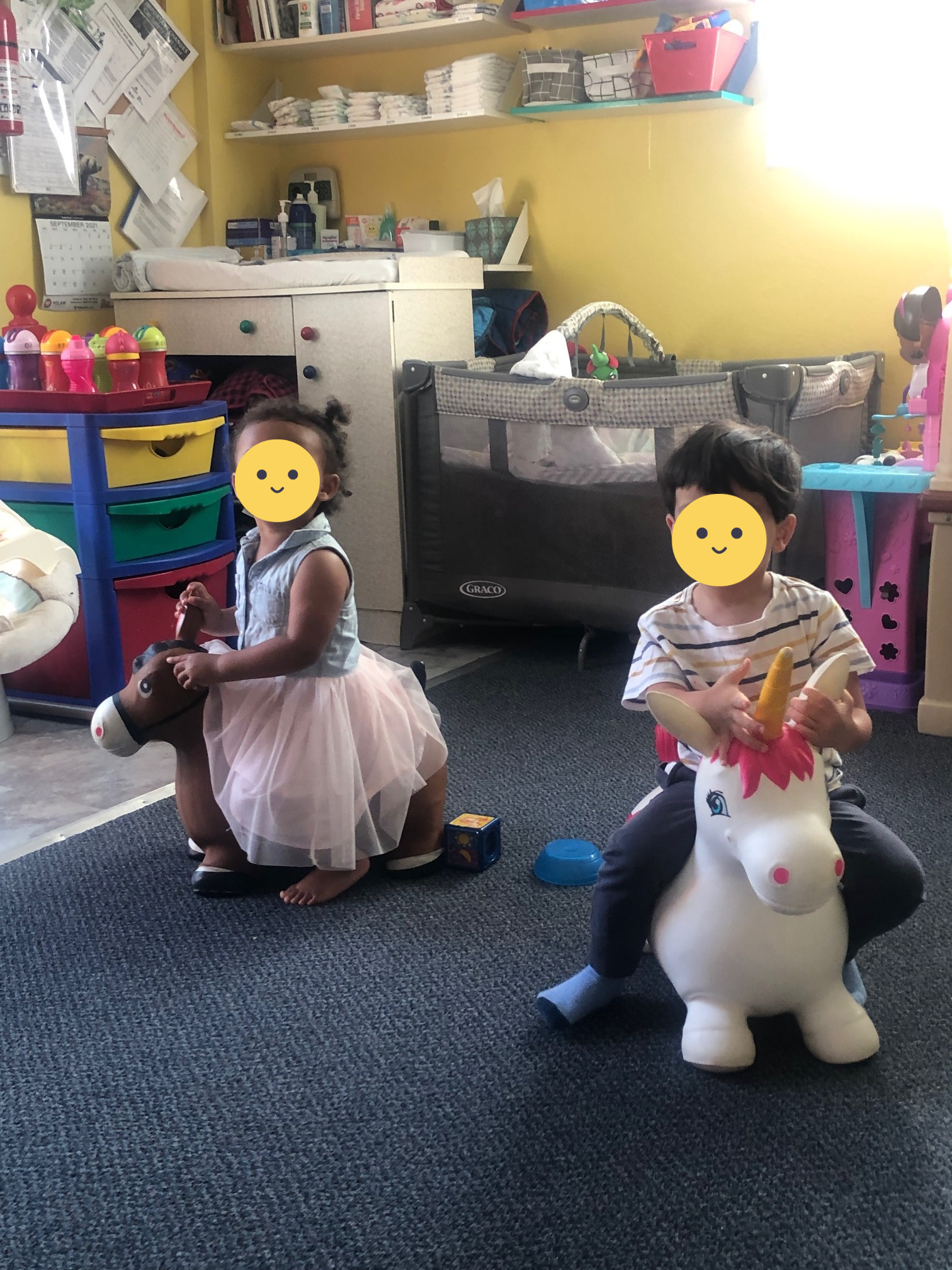 Two children riding a toy horse and toy unicorn.